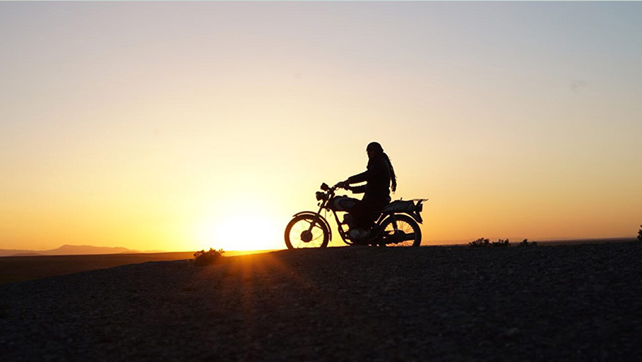 Woman riding motorcycle at sunset
