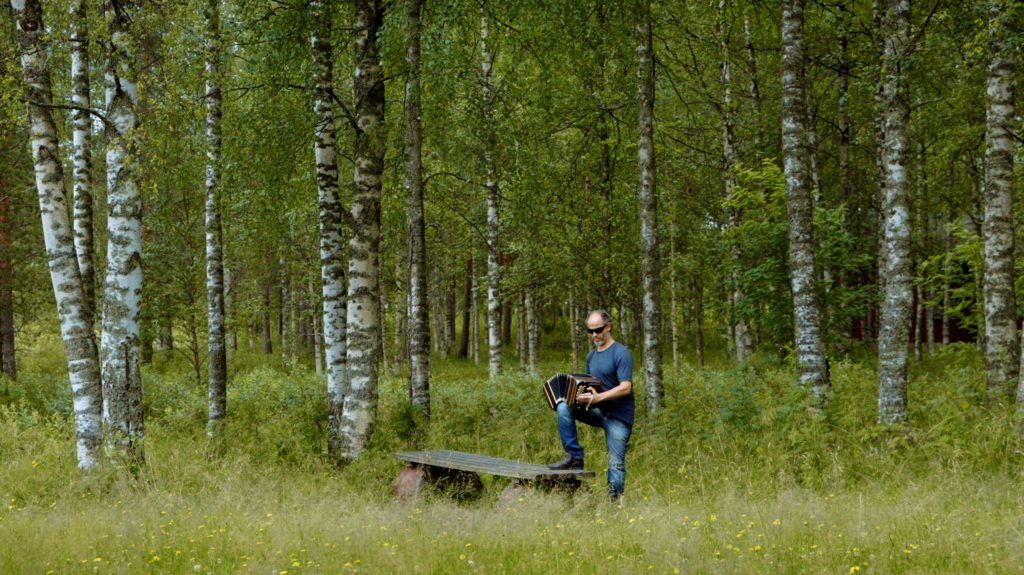 Man playing the accordian in the forest