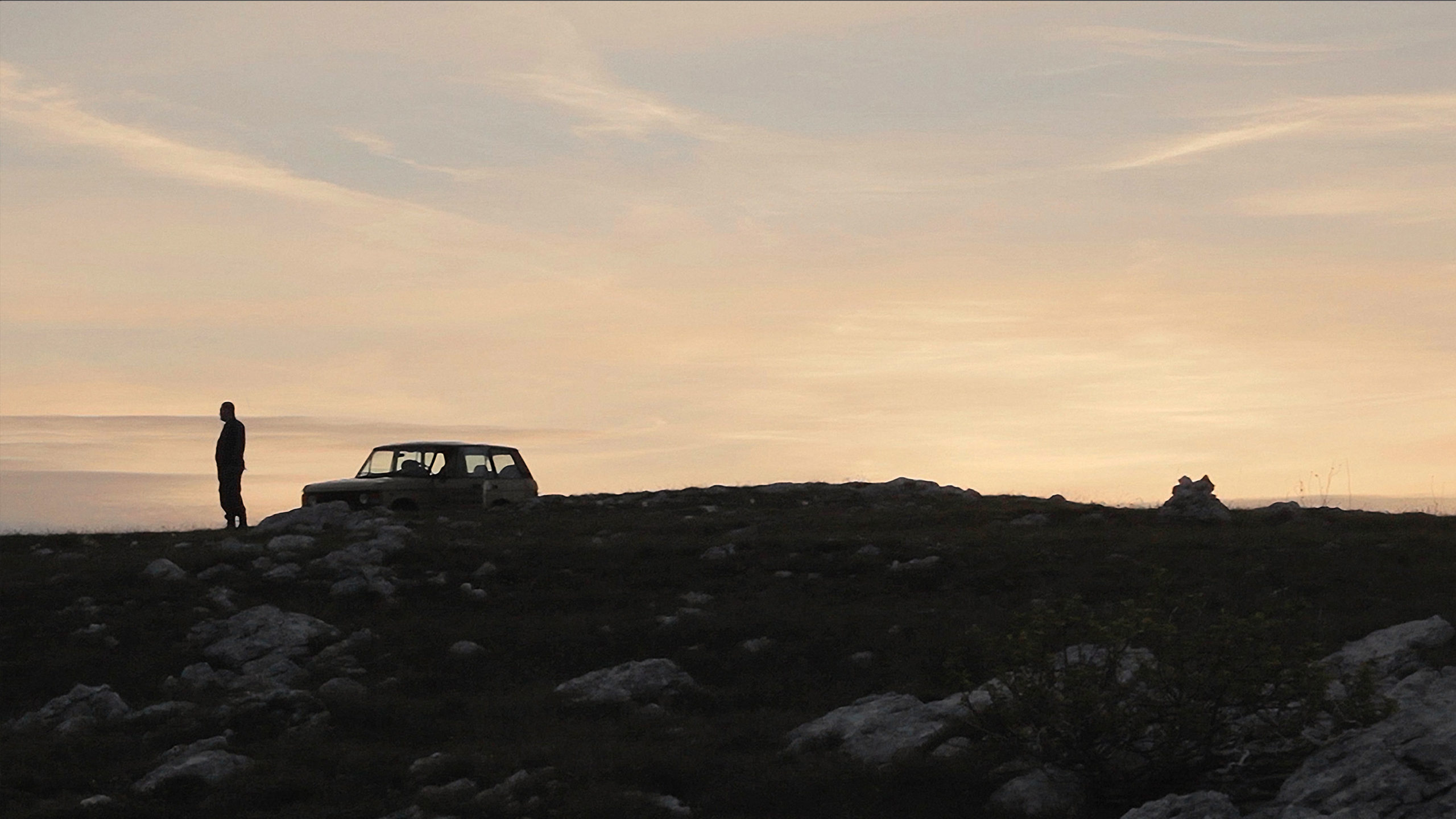 Car parked on coastal mountain at sunset