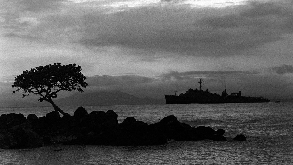 Old black and white photo with Military ship in the distance