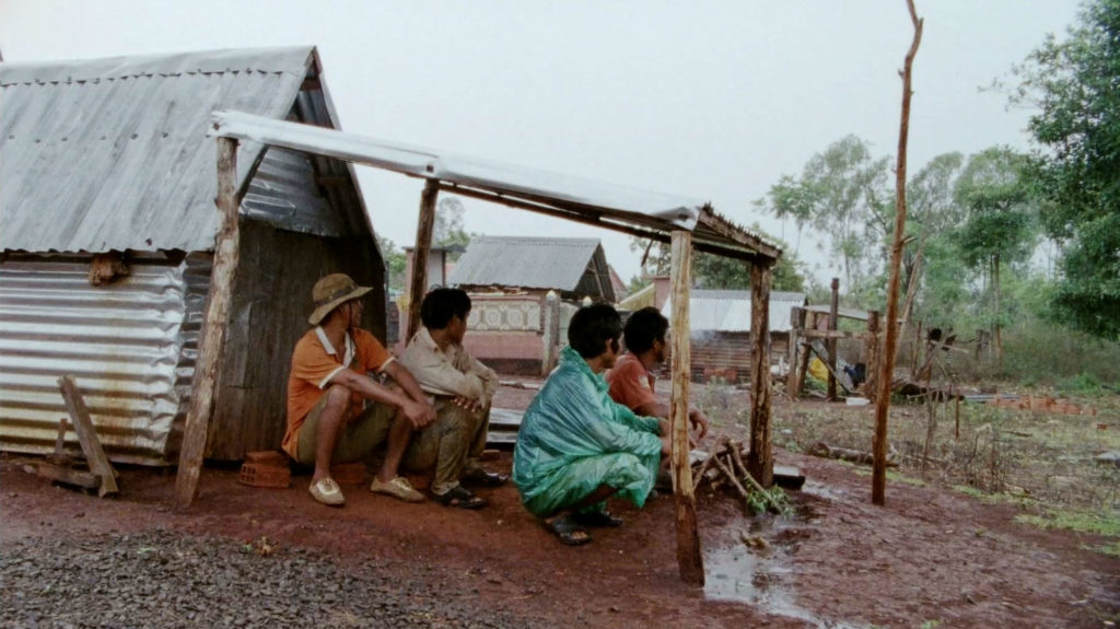 People sitting under rain shelter Vietnam village